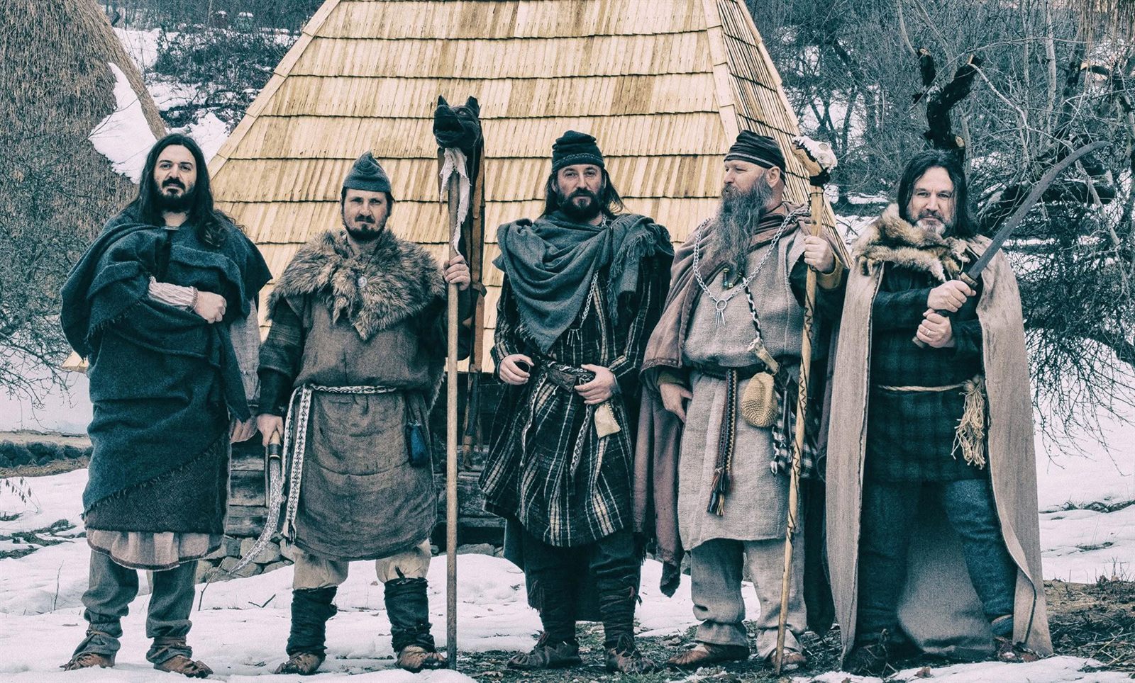Omnis Barbaria members in ancient dress, in winter, in front of a wooden house