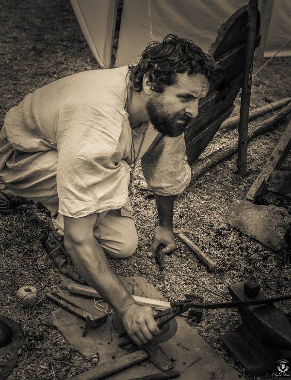 Blacksmith working at an anvil in the camp